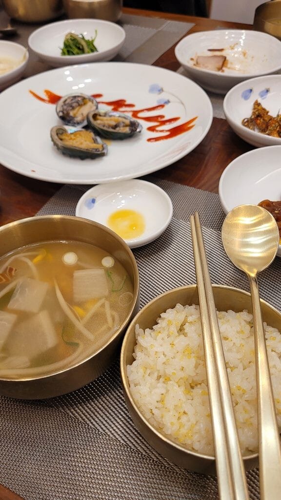 Korean rice and soup in brass bowls with metal spoon and chopsticks