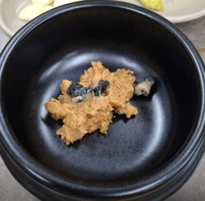 Individual earthenware pot of ssamjang with river snails