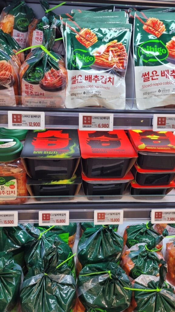 Small packs of sliced napa cabbage kimchi, young radish kimchi and ponytail radish kimchi in a Korean supermarket