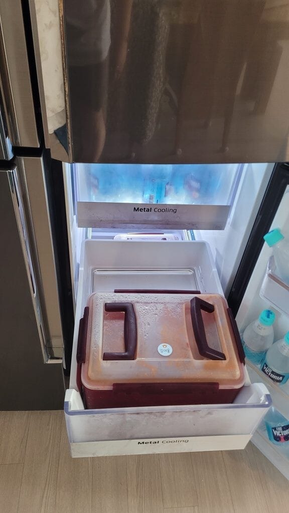 Open kimchi refrigerator drawer labeled Metal Cooling in a Korean home