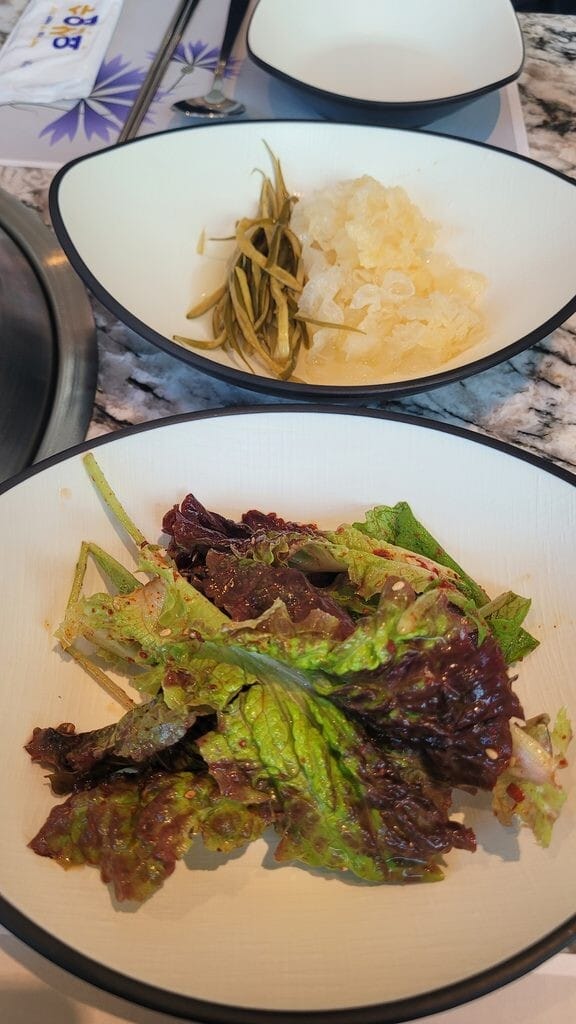 Korean side dishes including dressed lettuce salad, no ssam wrapping vegetables