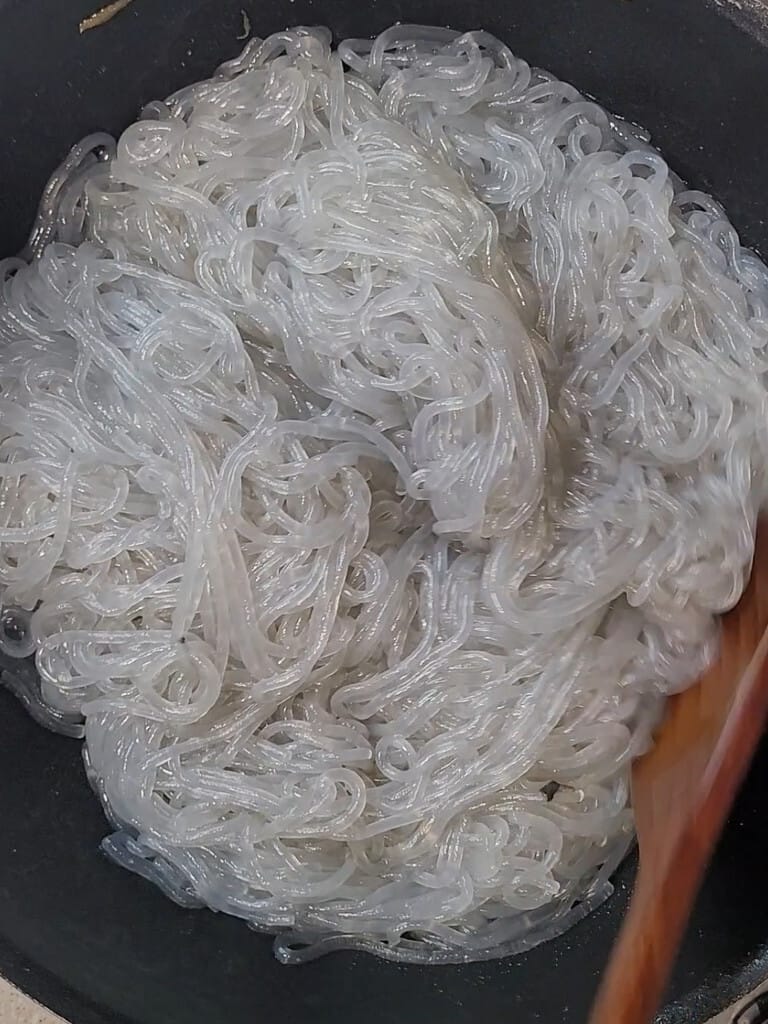 Boiled glass noodles frying dry in an empty pan before the sauce