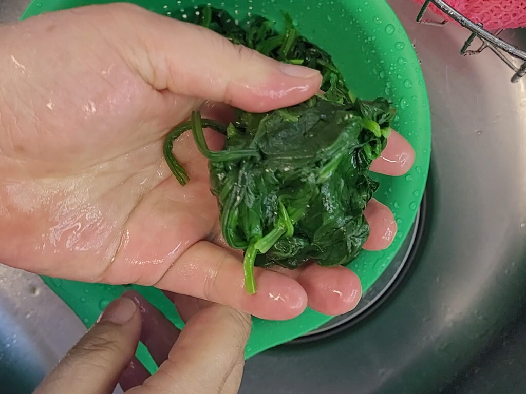Squeezing water out of blanched spinach by hand