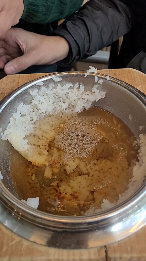 Pouring water into a rice pot to make sungnyung, Korean scorched-rice tea