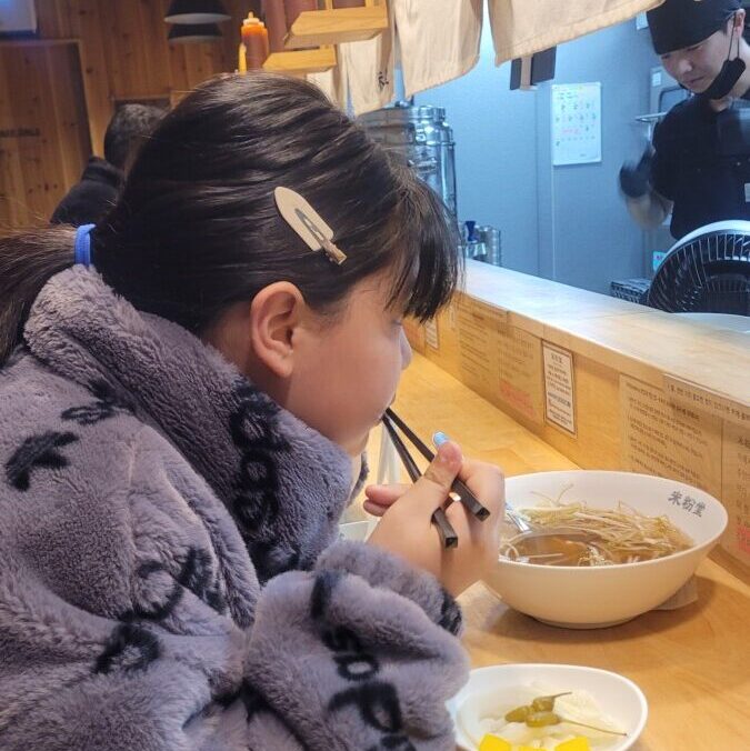 Counter seating facing the open kitchen at a Korean rice-noodle shop, built for solo diners