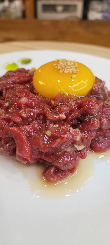 Yukhoe, Korean raw beef strips topped with an egg yolk and sesame seeds