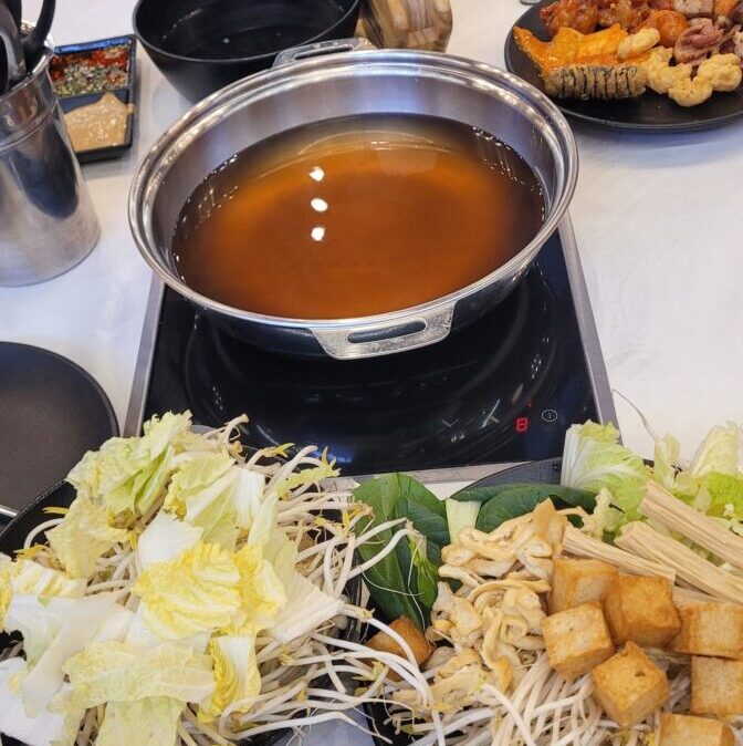 Shabu-shabu pot and vegetable plates at a Korean all-you-can-eat restaurant